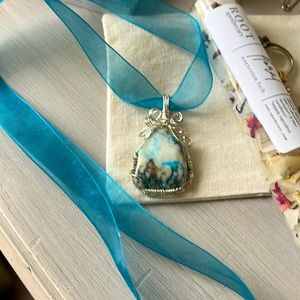 Turquoise colored  stone pendent with ribbon.